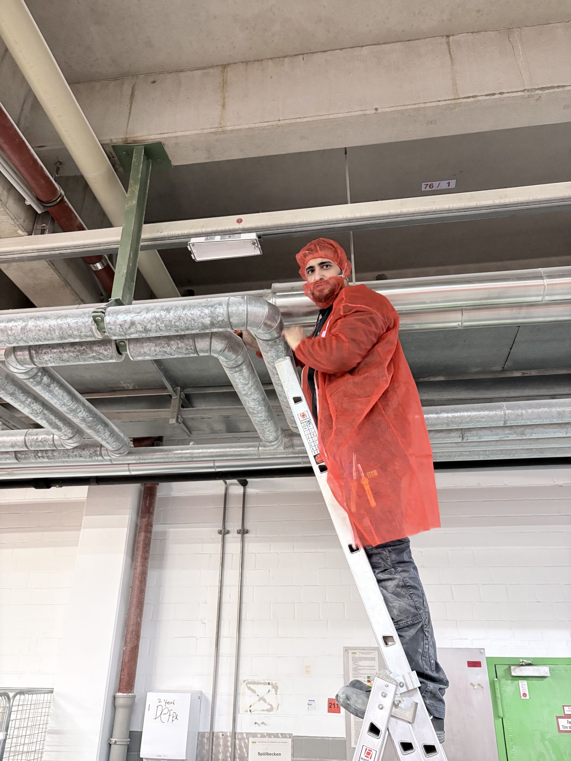 Elektriker von Zweering Elektrotechnik bei Installationsarbeiten an Leitungen in einer Industriehalle