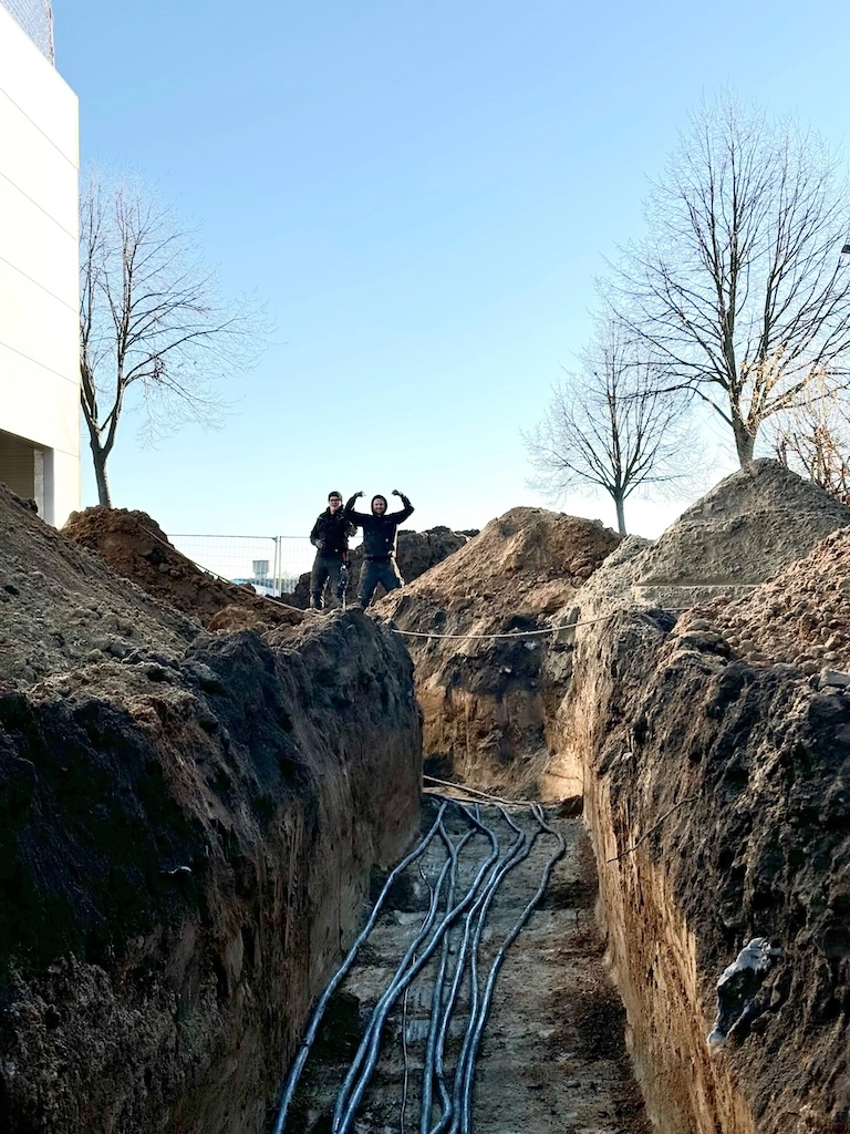 „Zweering-Mitarbeiter bei Erdarbeiten und dem Verlegen von Starkstromkabeln in einem offenen Kabelgraben.“
